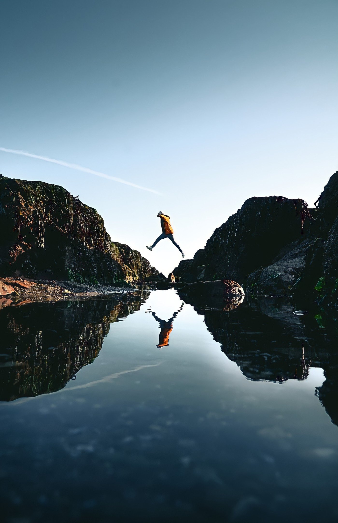 Person leaping between rocks over still water